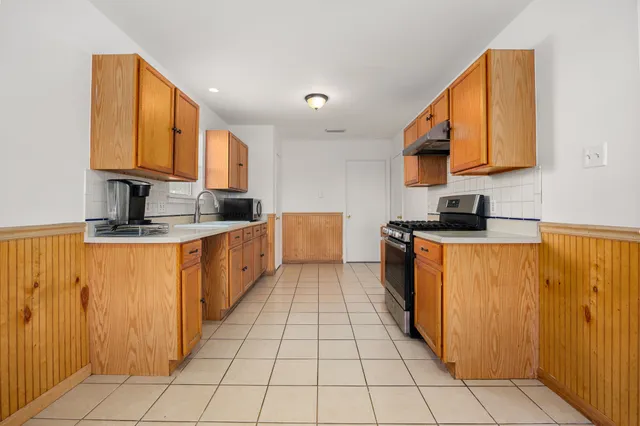a large kitchen with stainless steel appliances granite countertop a stove top oven a sink a counter space and cabinets