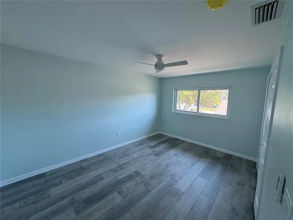 a view of an empty room with a window and wooden floor