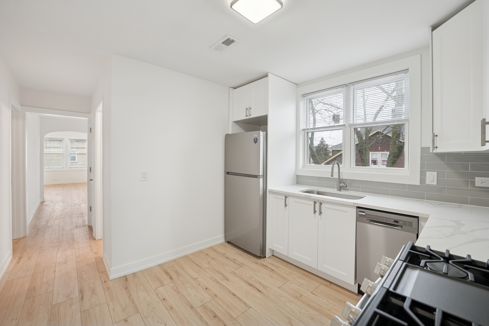 4954 West Byron Street Chicago, IL 60641 - Photo 2 of 33 a kitchen with granite countertop a refrigerator a sink dishwasher a stove and white countertops with wooden floor