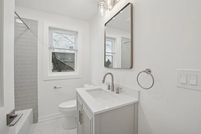 a bathroom with a toilet sink vanity and mirror