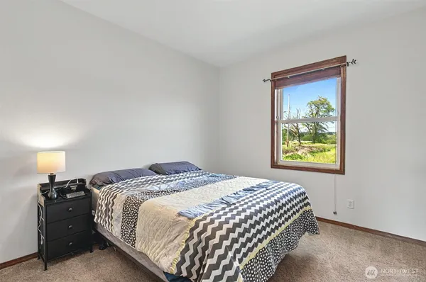 a bedroom with a bed and a lamp on dresser