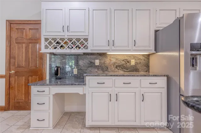 a kitchen with granite countertop white cabinets and stainless steel appliances