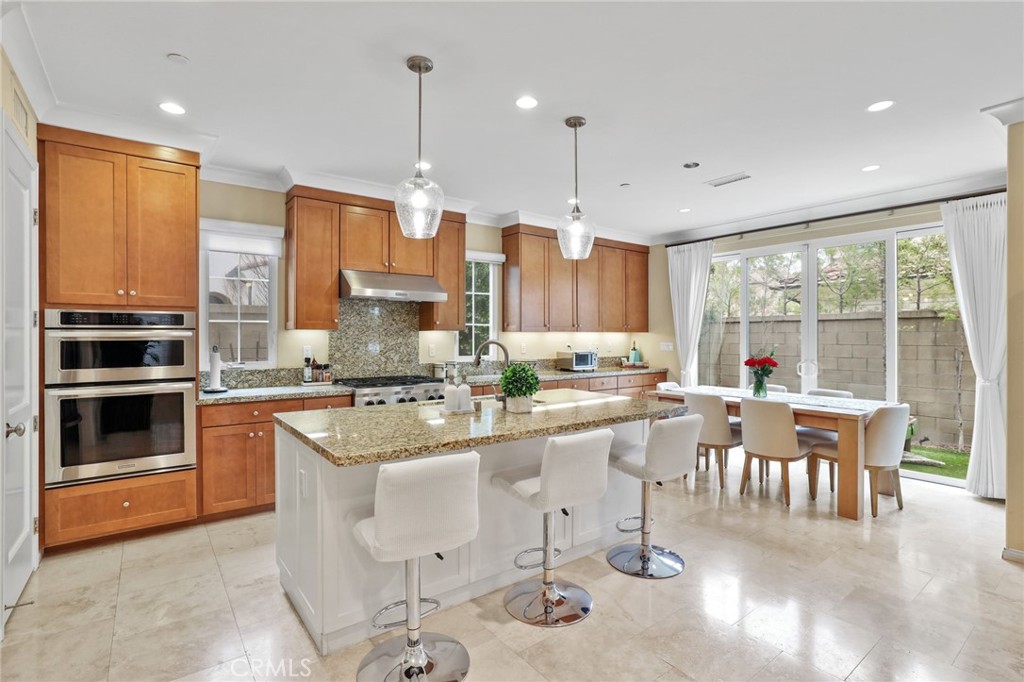 a kitchen with stainless steel appliances granite countertop a stove top oven a sink with dining table and chairs