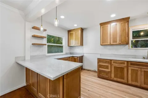a kitchen that has a sink a microwave oven a stove and white cabinets with wooden floor