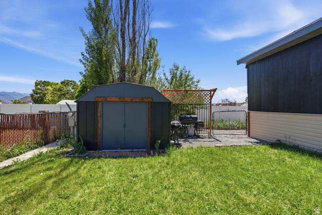 2500 North Fort Lane, Unit 220 Layton, UT 84041 - Photo 22 of 23 Expansive rear yard featuring a metal storage shed, gravel patio area, and perimeter fencing