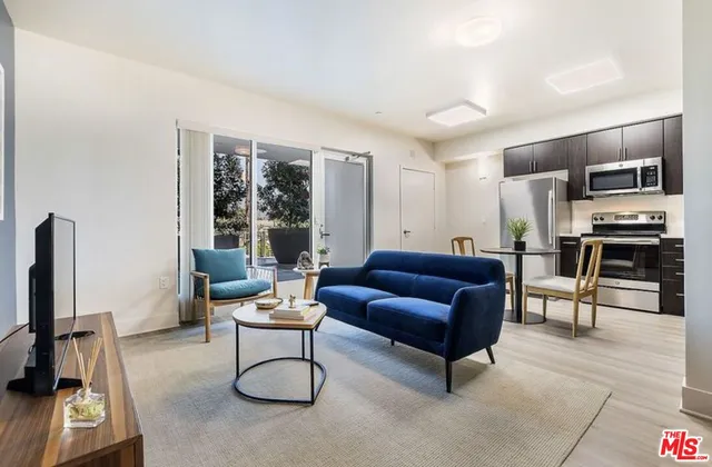 a living room with furniture a flat screen tv and a refrigerator