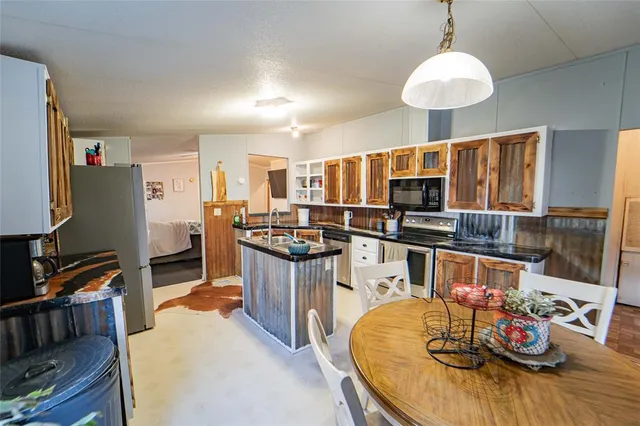 a kitchen with stainless steel appliances granite countertop a stove refrigerator and a dining table with wooden floor