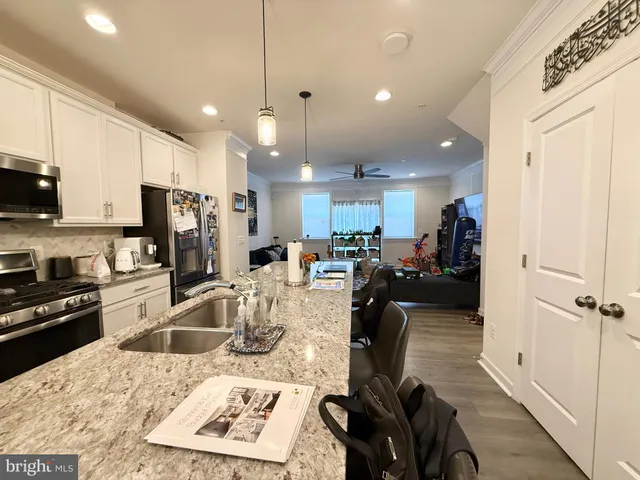 a kitchen with counter top space appliances and a view of living room