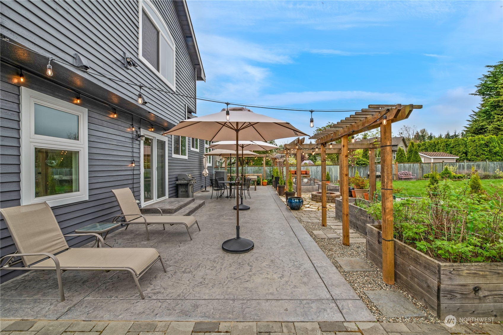 15014 Silver Firs Drive Everett, WA 98208 - Photo 25 of 30 a view of a patio with a table and chairs under an umbrella with a small garden