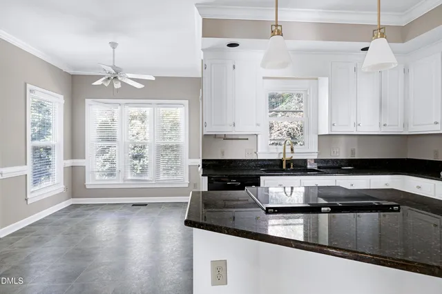 a kitchen with stainless steel appliances granite countertop a sink a stove and white cabinets
