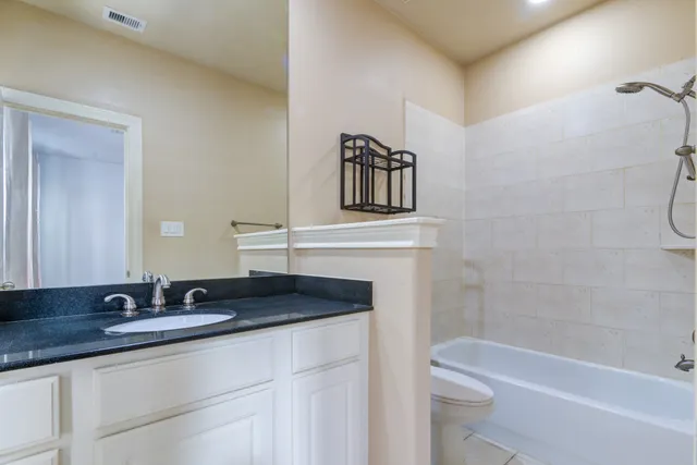 a bathroom with a granite countertop sink a toilet and bathtub