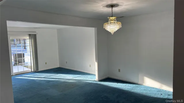 a view of a room with a chandelier fan and wooden floor