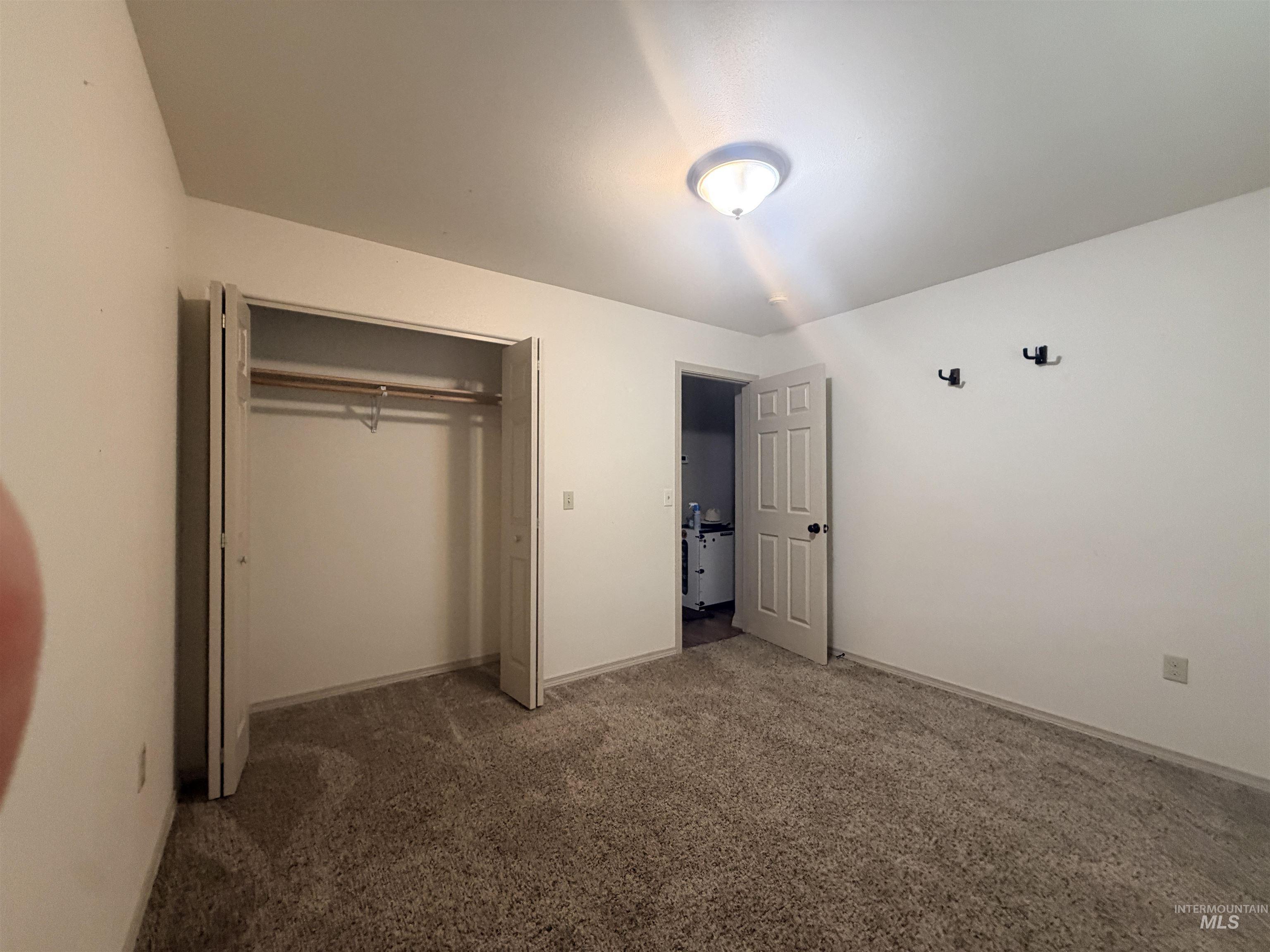 1028 Granlund Road Troy, ID 83871 - Photo 11 of 35 Carpeted room featuring a ceiling-mounted light fixture, bi-fold closet doors, a clothing rod, and wall-mounted hooks