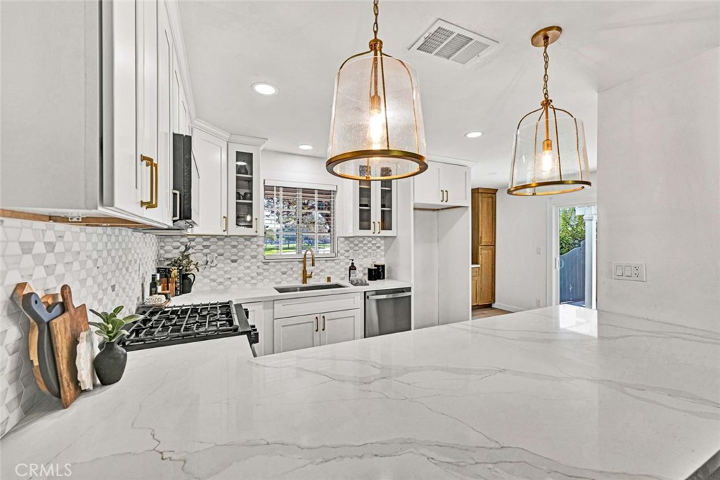5331 Cerulean Avenue Garden Grove, CA 92845 - Photo 5 of 44 a large white kitchen with granite countertop a sink a stove and a wooden floors