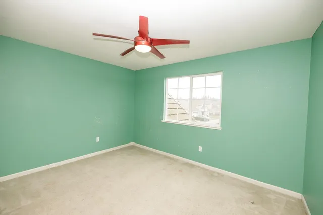 an empty room with ceiling fan and window