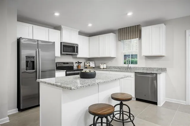 a kitchen with stainless steel appliances granite countertop a stove a sink a refrigerator and white cabinets
