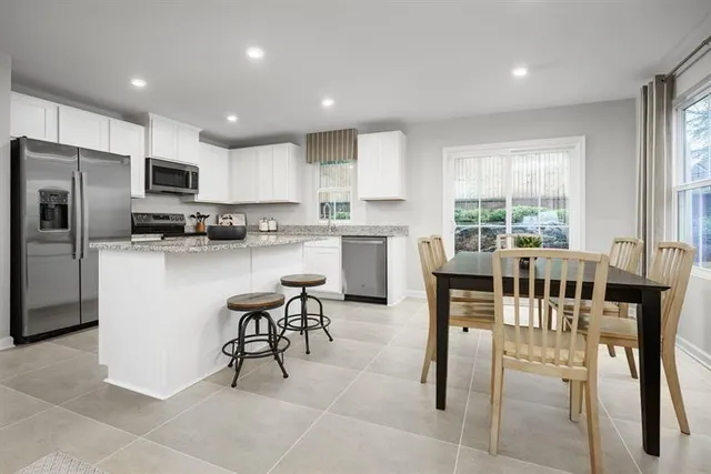a kitchen with stainless steel appliances kitchen island granite countertop a table and chairs in it