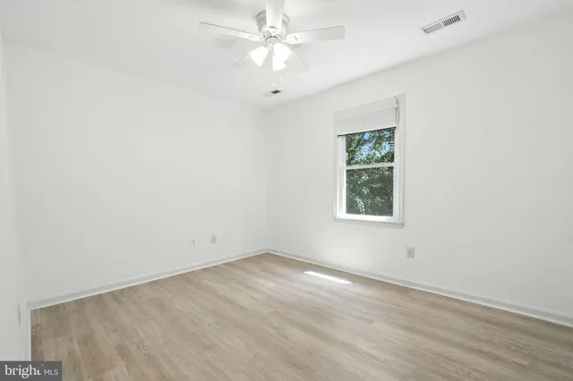 an empty room with a window and a fan