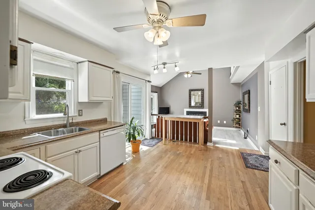 a large white kitchen with a large window stainless steel appliances a sink and cabinets