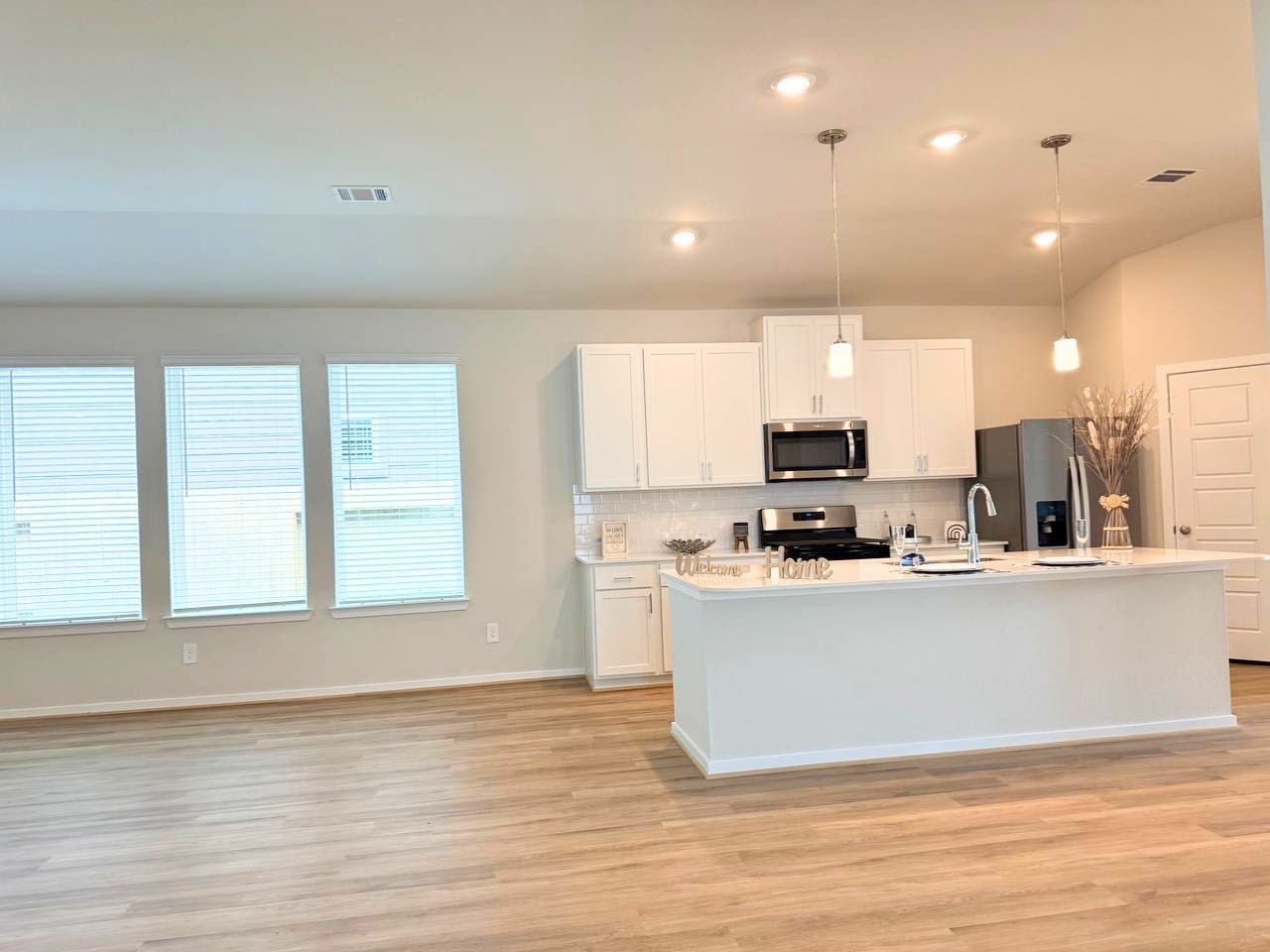 16246 Parish Pointe Court Conroe, TX 77302 - Photo 19 of 32 a kitchen with stainless steel appliances a refrigerator a stove top oven and a sink with wooden floor