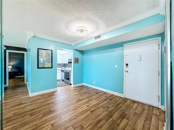 a view of a big room with wooden floor and a kitchen