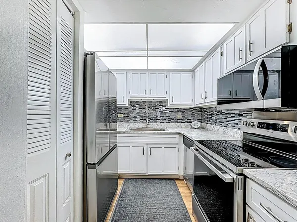 a kitchen with stainless steel appliances granite countertop a stove a sink and a microwave