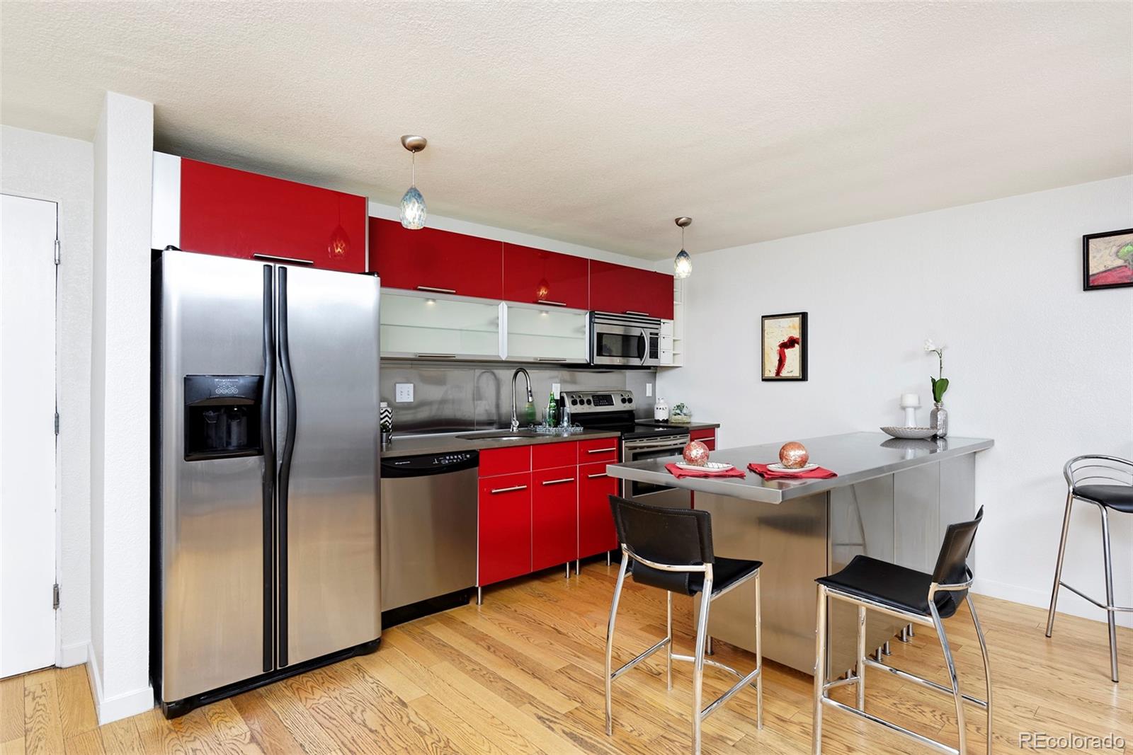 75 Emerson Street, Unit 103 Denver, CO 80218 - Photo 3 of 19 a kitchen with stainless steel appliances kitchen island granite countertop a kitchen island a table and chairs in it