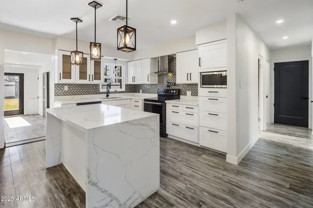 a kitchen with stainless steel appliances kitchen island granite countertop a stove a sink and a refrigerator