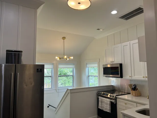 a kitchen with stainless steel appliances granite countertop a refrigerator a stove a sink and a microwave with wooden floor