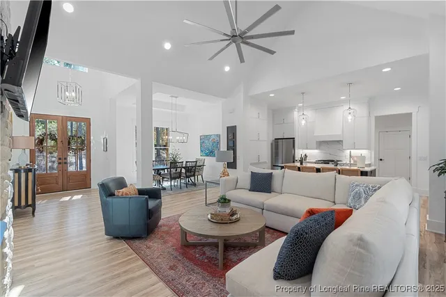 a living room with furniture a rug kitchen view and a chandelier