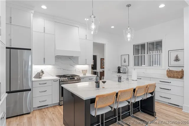 a kitchen with a sink a stove a refrigerator and white cabinets with wooden floor