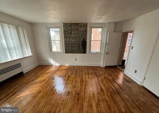 an empty room with wooden floor and windows