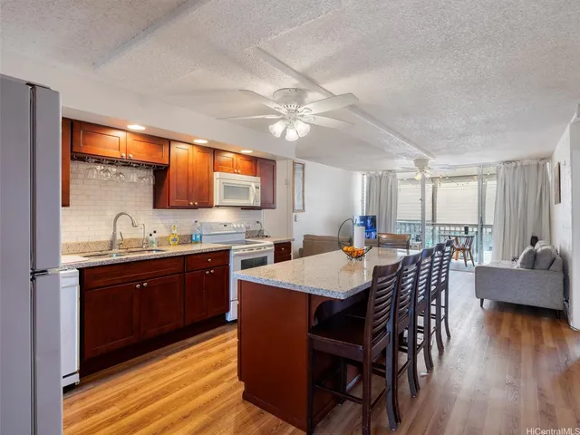 a kitchen with stainless steel appliances granite countertop a sink a stove a dining table and chairs