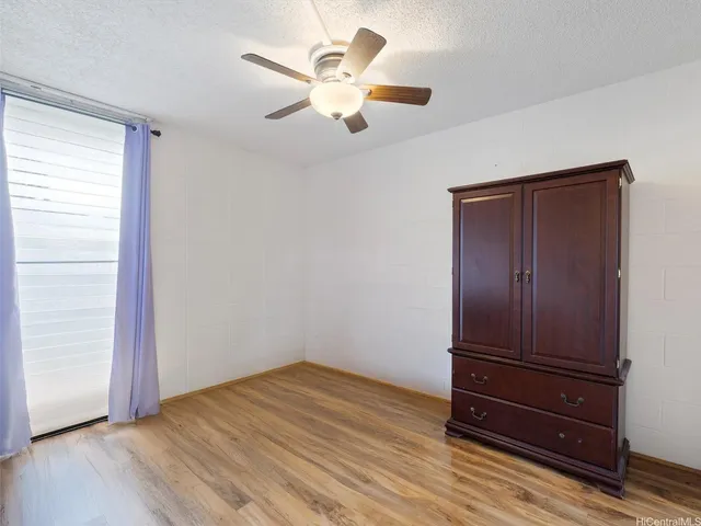 an empty room with wooden floor closet and ceiling fan
