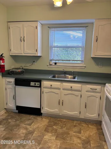 a kitchen with white cabinets and sink