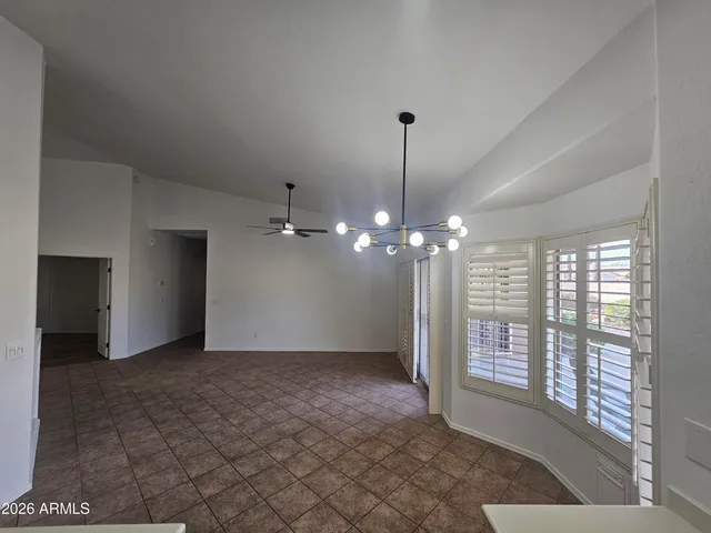 a view of an empty room with window and chandelier fan