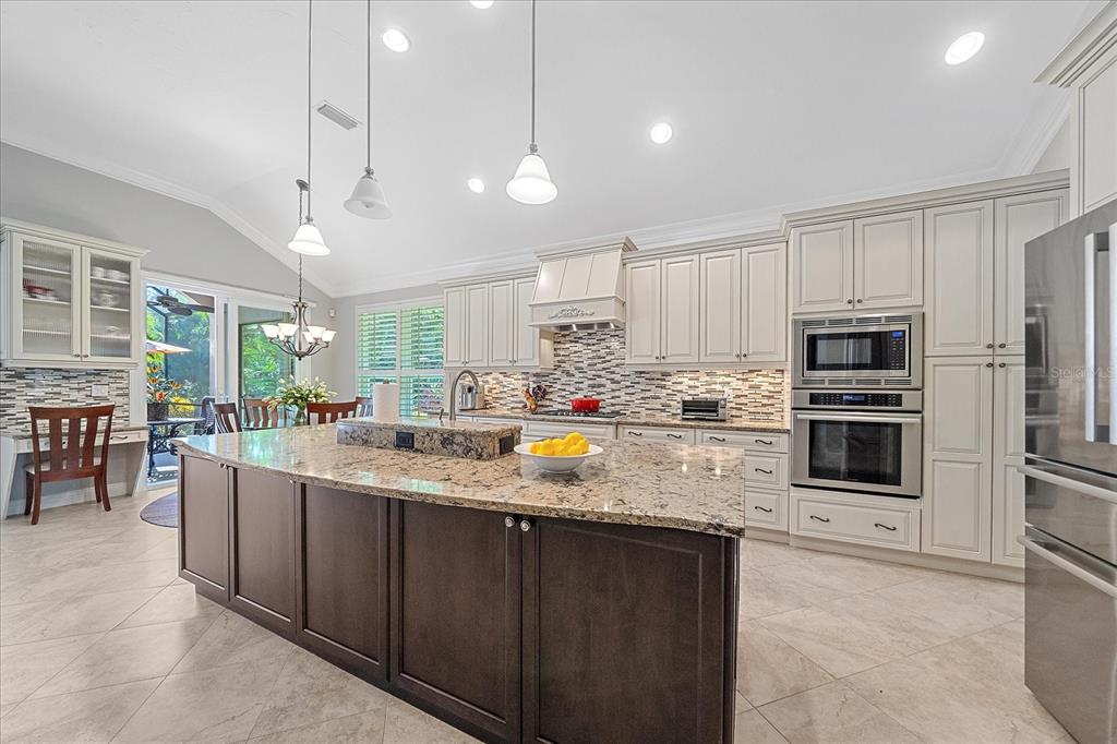7825 Troon Court Lakewood Ranch, FL 34202 - Photo 14 of 40 a kitchen with stainless steel appliances granite countertop a refrigerator a sink a stove a oven a dining table and chairs