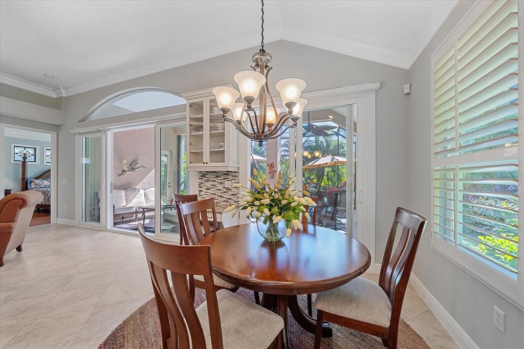 7825 Troon Court Lakewood Ranch, FL 34202 - Photo 16 of 40 a view of a dining room with furniture a chandelier and wooden floor