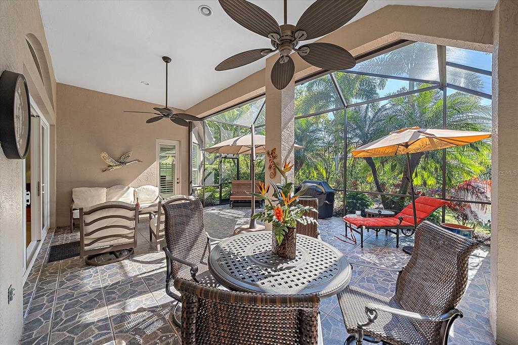 7825 Troon Court Lakewood Ranch, FL 34202 - Photo 36 of 40 a dining room with furniture a floor to ceiling window and a flat screen tv