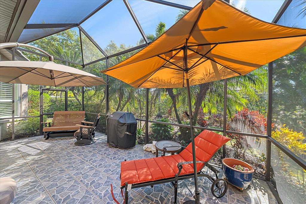 7825 Troon Court Lakewood Ranch, FL 34202 - Photo 37 of 40 a backyard view of a house with basket ball table and chairs under an umbrella