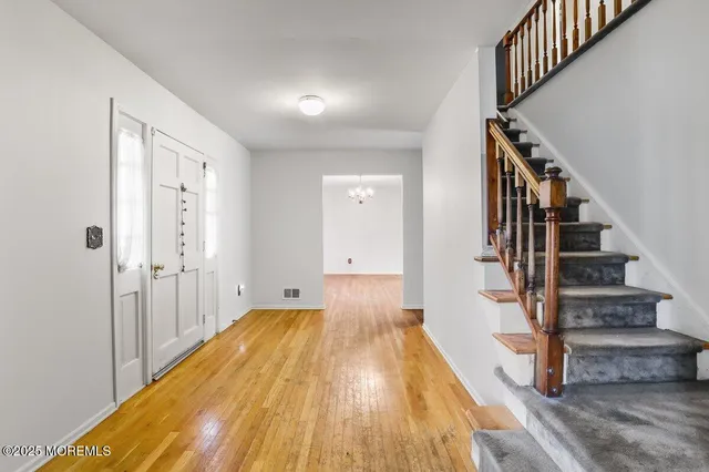 a view of a hallway with wooden floor and staircase