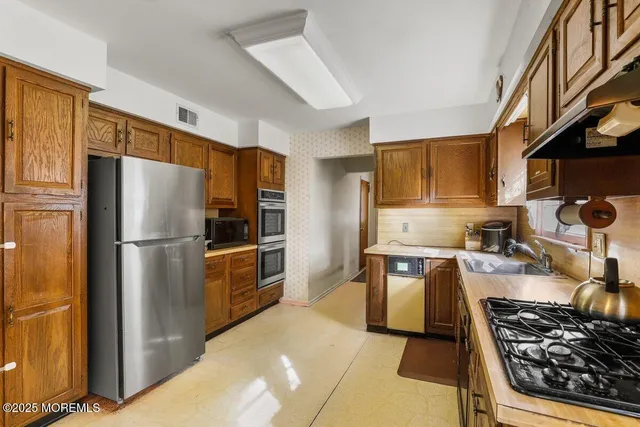 a kitchen with stainless steel appliances granite countertop a refrigerator stove and sink