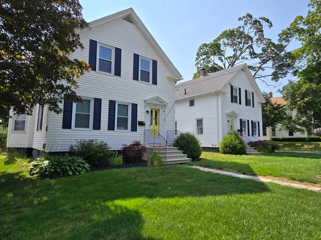 a front view of a house with a garden and trees