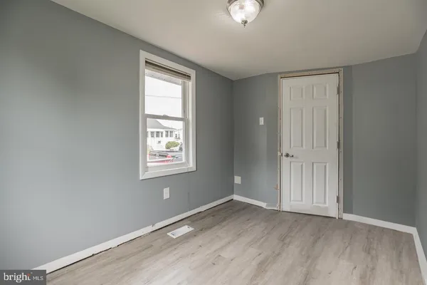 an empty room with wooden floor cabinet and windows