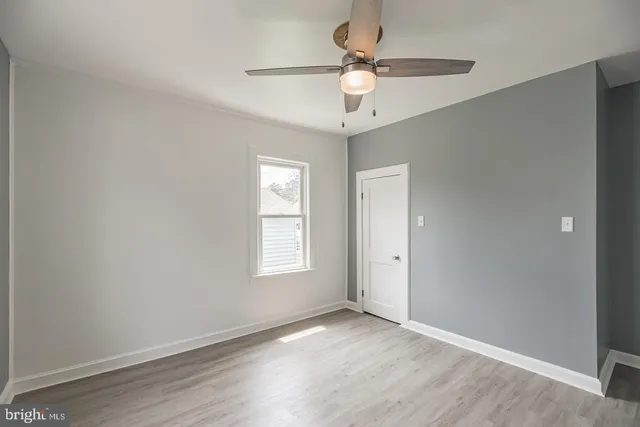 an empty room with wooden floor fan and windows
