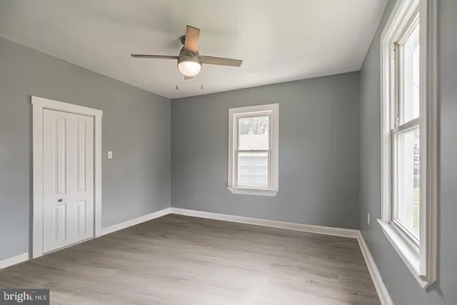 a view of empty room with wooden floor and fan