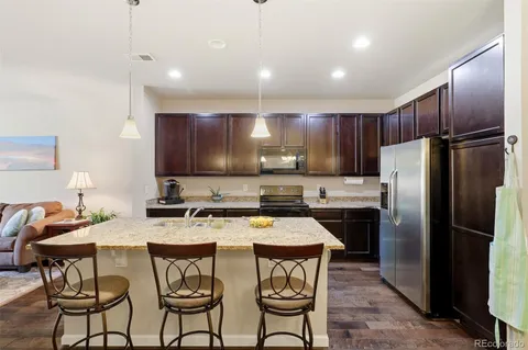 a kitchen with stainless steel appliances granite countertop a stove a refrigerator a sink a stove a dining table and chairs