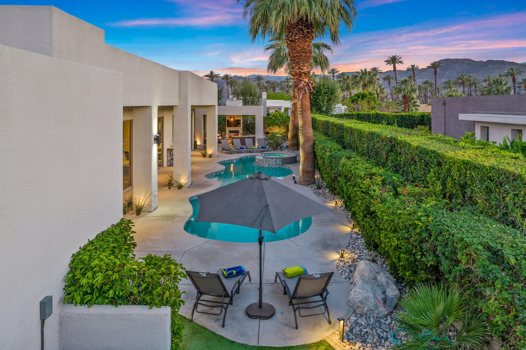 36725 Palm View Road Rancho Mirage, CA 92270 - Photo 10 of 136 a view of a patio with couches table and chairs under an umbrella with palm trees