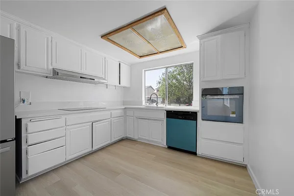 a kitchen with white cabinets and window
