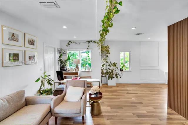a living room with furniture a potted plant and a large window